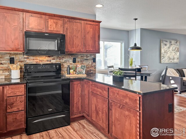 kitchen featuring decorative backsplash, a peninsula, light wood finished floors, dark stone countertops, and black appliances
