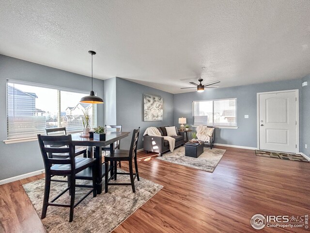 dining area with baseboards, wood finished floors, ceiling fan, and a textured ceiling