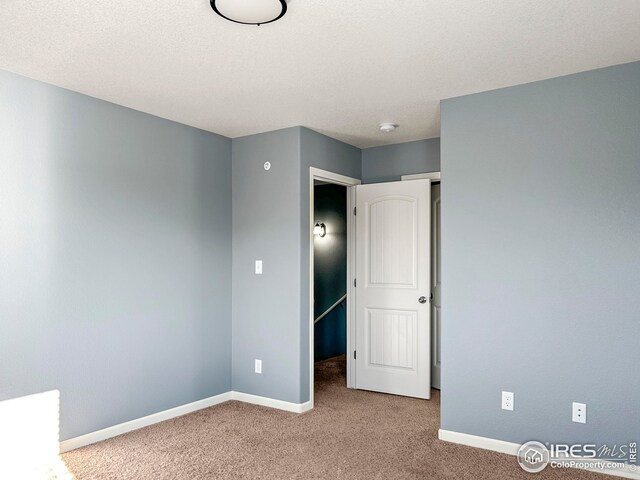 unfurnished bedroom with carpet flooring, baseboards, and a textured ceiling