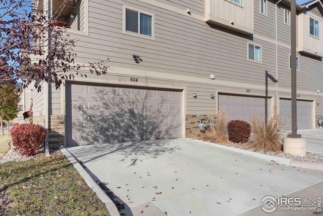 exterior space with driveway, stone siding, and an attached garage