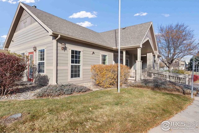 view of side of home with a shingled roof and a yard