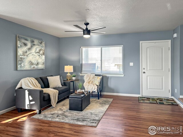 living area with wood finished floors, a textured ceiling, baseboards, and ceiling fan