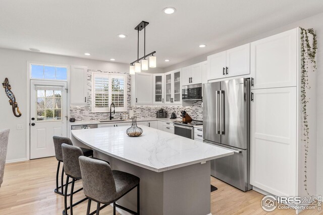 kitchen with decorative backsplash, a kitchen bar, stainless steel appliances, a sink, and a center island