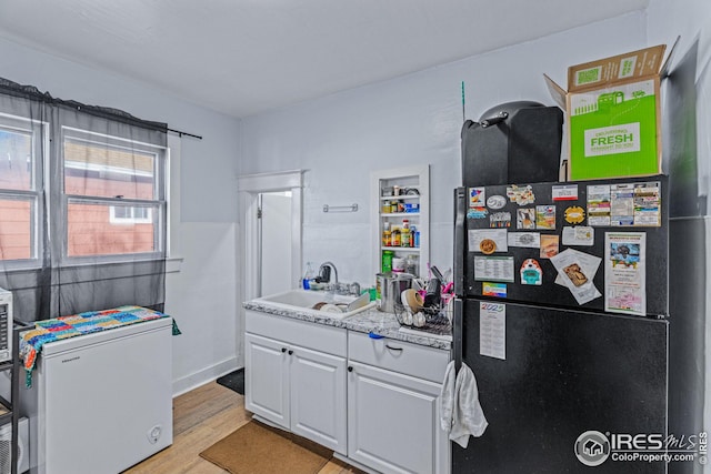 919 State St, Fort Morgan, CO 80701 - kitchen with a sink, freestanding refrigerator, white refrigerator, white cabinets, and light wood-style flooring