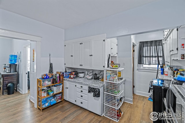 919 State St, Fort Morgan, CO 80701 - kitchen featuring wood finished floors, white cabinets, light stone countertops, baseboards, and washer / clothes dryer