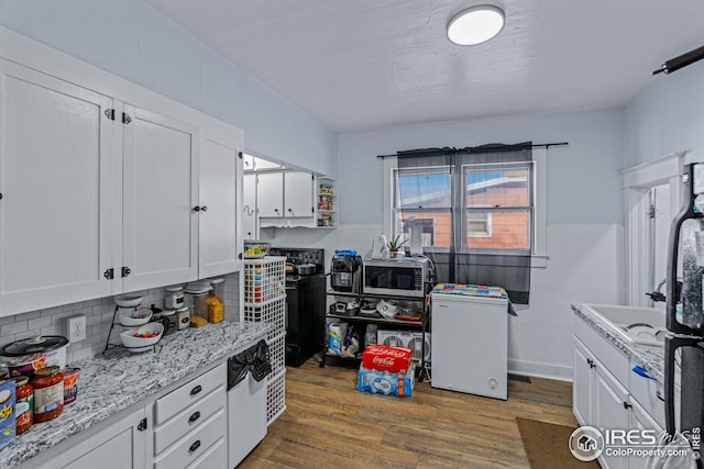 919 State St, Fort Morgan, CO 80701 - kitchen featuring stainless steel microwave, white cabinetry, wood finished floors, backsplash, and a sink