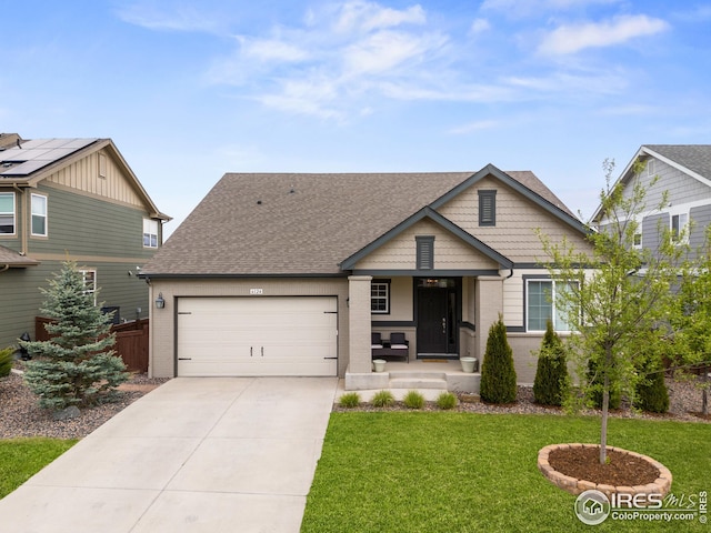 view of front of home with concrete driveway, roof with shingles, an attached garage, a front yard, and brick siding