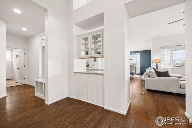 hall with dark wood finished floors, baseboards, recessed lighting, and a sink