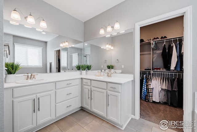 bathroom featuring a spacious closet, double vanity, a sink, and tile patterned flooring