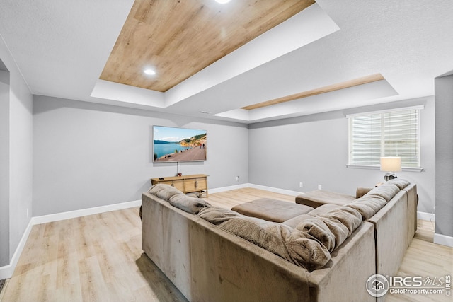 living room with light wood-style flooring, wooden ceiling, a tray ceiling, and baseboards