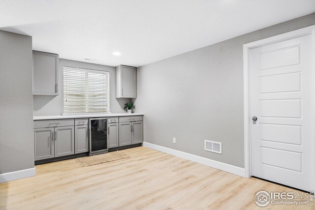kitchen featuring visible vents, gray cabinets, light wood-style floors, and beverage cooler