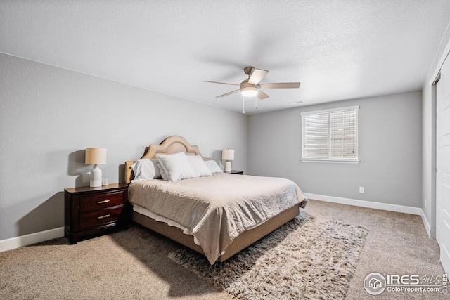bedroom featuring light carpet, a textured ceiling, baseboards, and ceiling fan