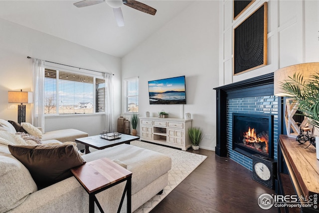 living room with high vaulted ceiling, a tile fireplace, dark wood-type flooring, and ceiling fan