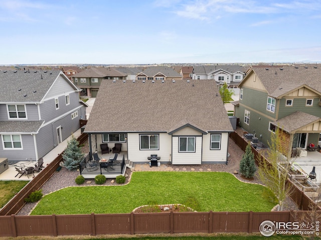 back of house with a fenced backyard, a residential view, and roof with shingles