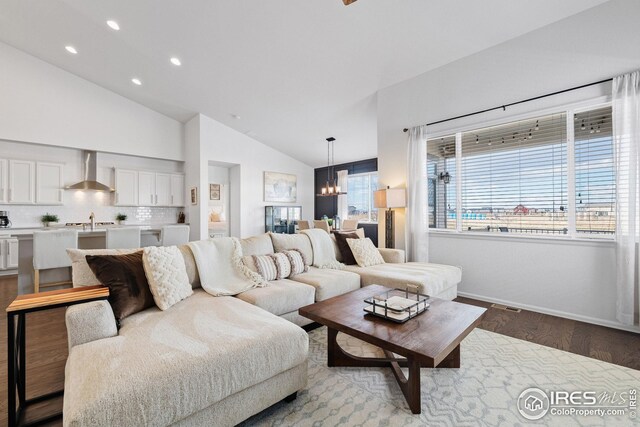 living room with high vaulted ceiling, a chandelier, baseboards, wood finished floors, and recessed lighting