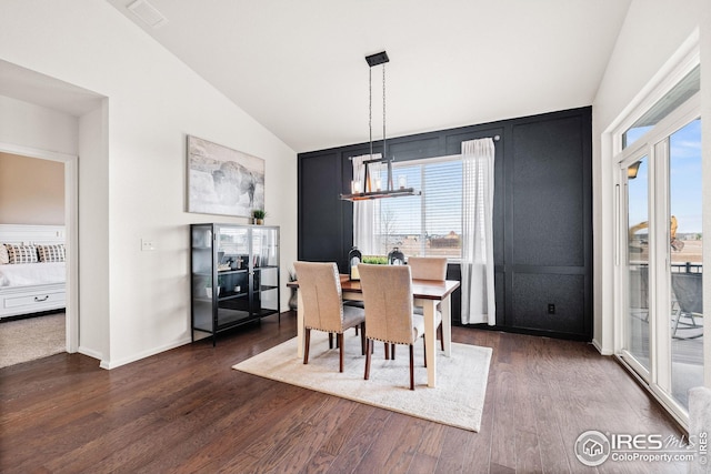 dining area featuring dark wood finished floors, baseboards, a notable chandelier, and vaulted ceiling