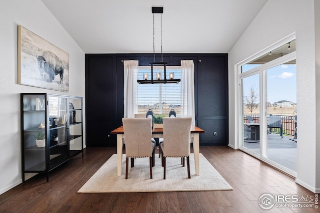 dining area with an inviting chandelier, dark wood-style floors, lofted ceiling, and baseboards