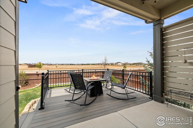 deck featuring a rural view, a fire pit, and fence