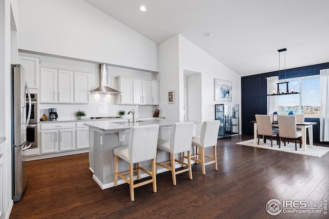 kitchen featuring light countertops, a kitchen bar, an inviting chandelier, dark wood finished floors, and wall chimney exhaust hood