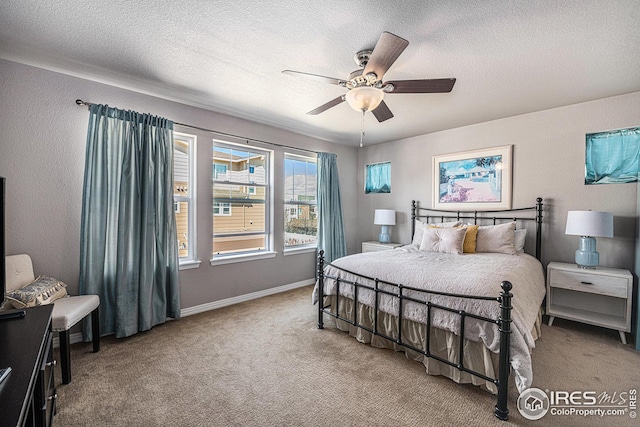 carpeted bedroom with baseboards, ceiling fan, and a textured ceiling