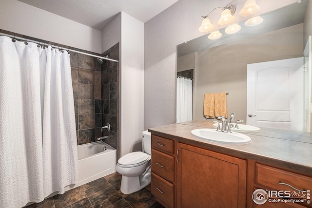 bathroom featuring toilet, vanity, stone finish floor, and shower / tub combo with curtain