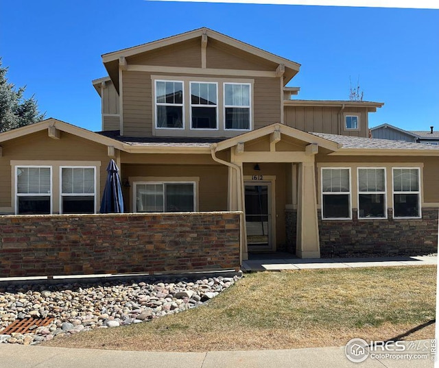craftsman inspired home with stone siding, board and batten siding, and a fenced front yard