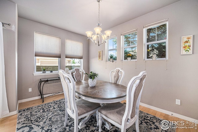 dining room featuring light wood-style flooring, baseboards, and a chandelier