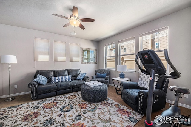 carpeted living room featuring baseboards, a textured ceiling, and ceiling fan