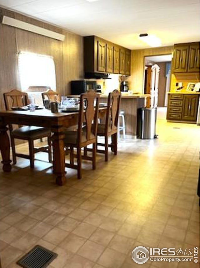 dining space with visible vents, wooden walls, and light floors