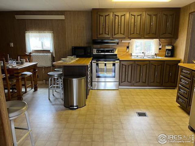 kitchen featuring light countertops, stainless steel range with electric cooktop, light floors, under cabinet range hood, and black microwave