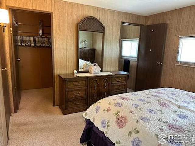 bedroom featuring wood walls and light colored carpet