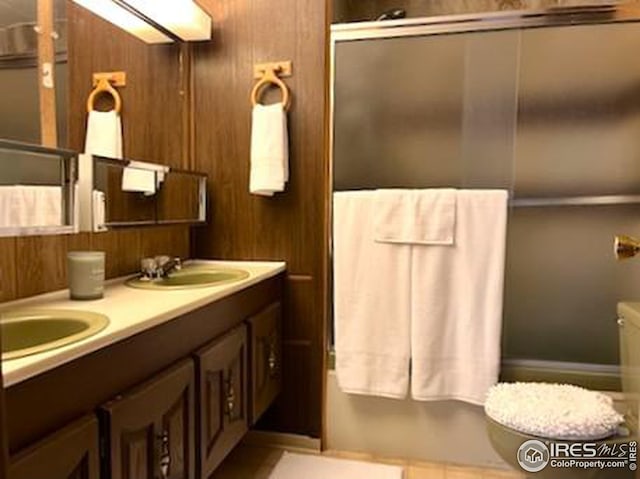 full bathroom featuring double vanity, a sink, and wooden walls