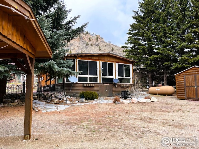 back of house featuring an outbuilding, a storage unit, and log veneer siding
