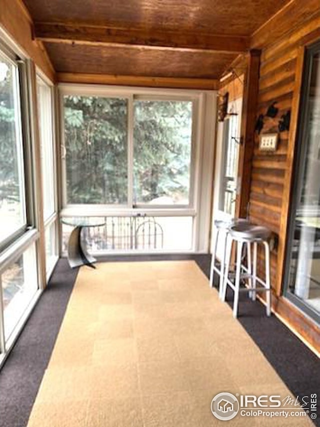 unfurnished sunroom with beam ceiling and wood ceiling