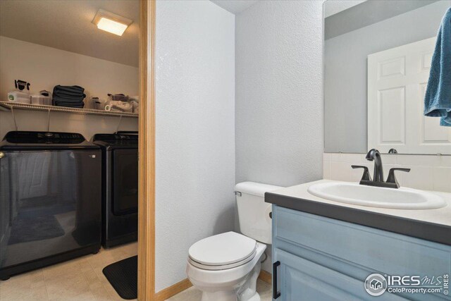 1725 67th Ave, Greeley, CO 80634 - bathroom featuring vanity, toilet, washer and clothes dryer, and tasteful backsplash