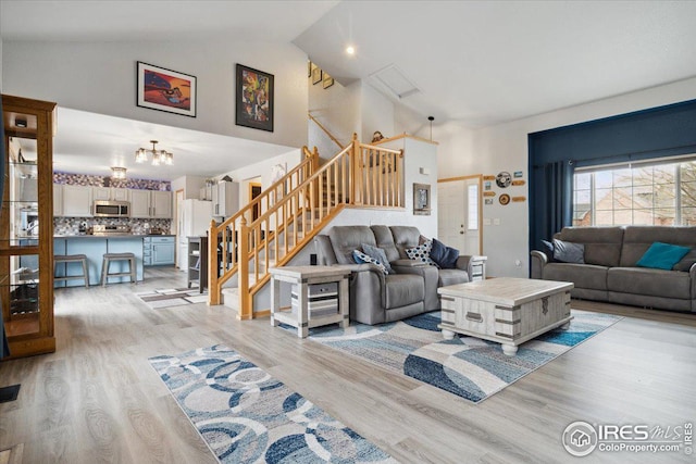1725 67th Ave, Greeley, CO 80634 - living room featuring a notable chandelier, high vaulted ceiling, light wood-style floors, and stairway