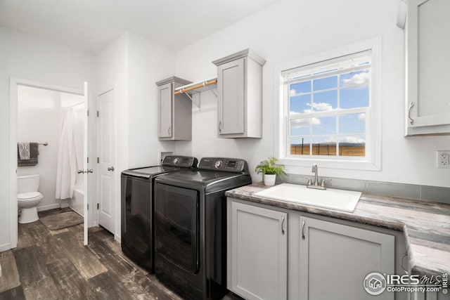 laundry room with dark wood-style flooring, a sink, cabinet space, and washer and dryer