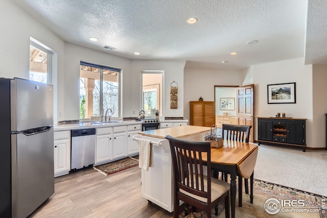 kitchen featuring light countertops, a sink, appliances with stainless steel finishes, visible vents, and white cabinets