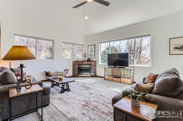 living area featuring high vaulted ceiling, carpet, baseboards, ceiling fan, and a high end fireplace