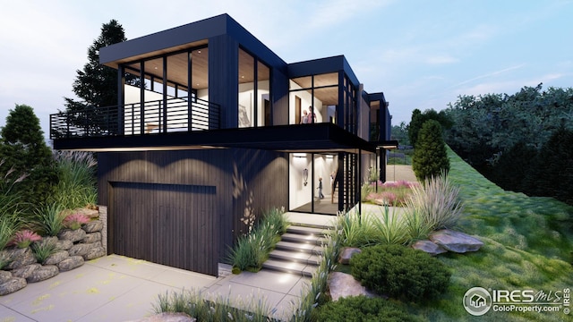 view of front facade featuring driveway, an attached garage, and a balcony