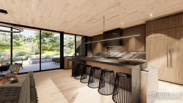 interior space with wood ceiling, dark countertops, a sink, light wood-type flooring, and floor to ceiling windows