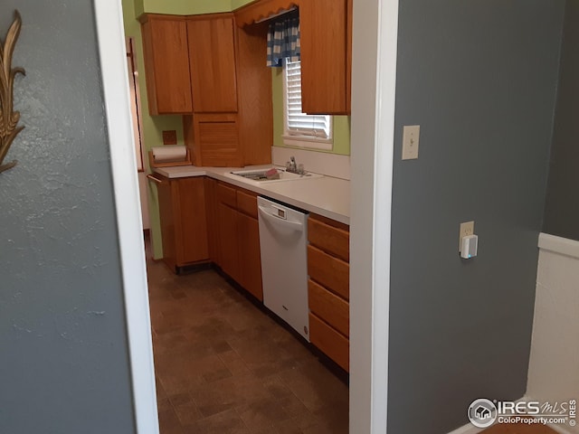 kitchen featuring white dishwasher, a sink, brown cabinets, and light countertops