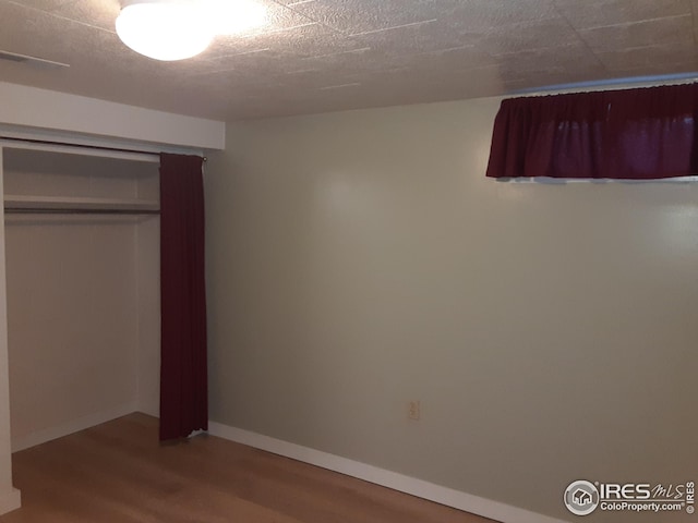 unfurnished bedroom featuring baseboards, a closet, and wood finished floors