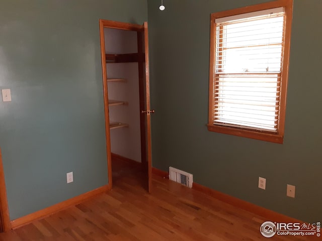 spare room featuring baseboards, visible vents, a healthy amount of sunlight, and wood finished floors