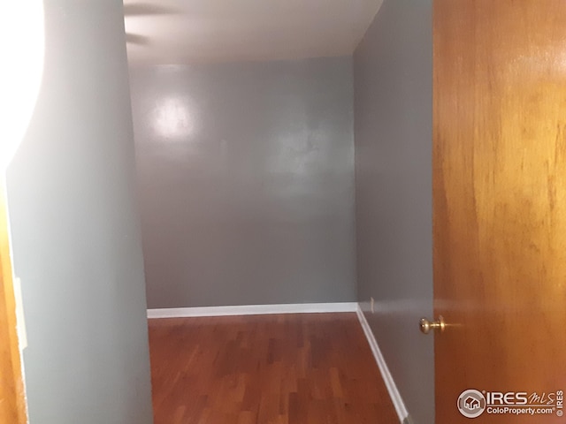 hallway featuring baseboards and wood finished floors