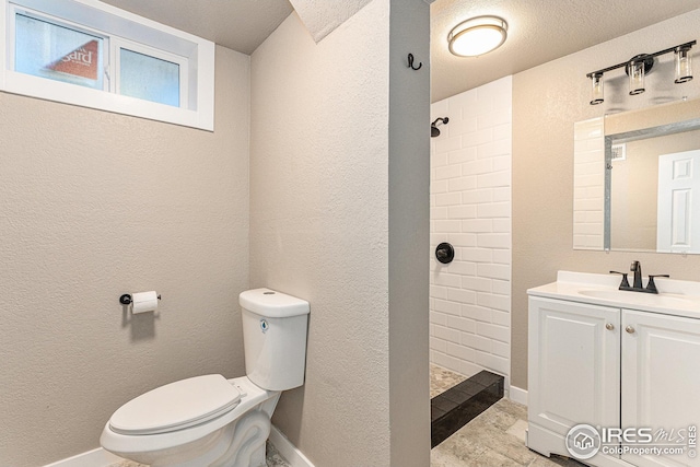191 Emerald St, Broomfield, CO 80020 - bathroom with toilet, tiled shower, vanity, baseboards, and a textured wall