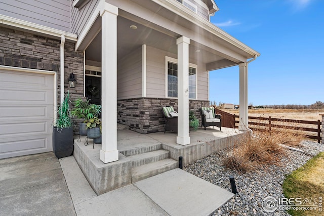 view of patio / terrace featuring fence, covered porch, and a garage