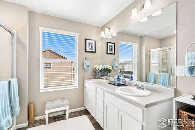 full bathroom featuring a shower stall, double vanity, baseboards, and a sink