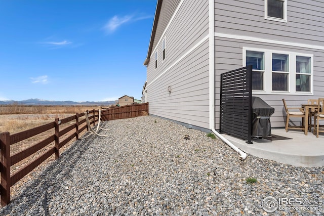 view of side of property with a fenced backyard, a patio area, and a mountain view