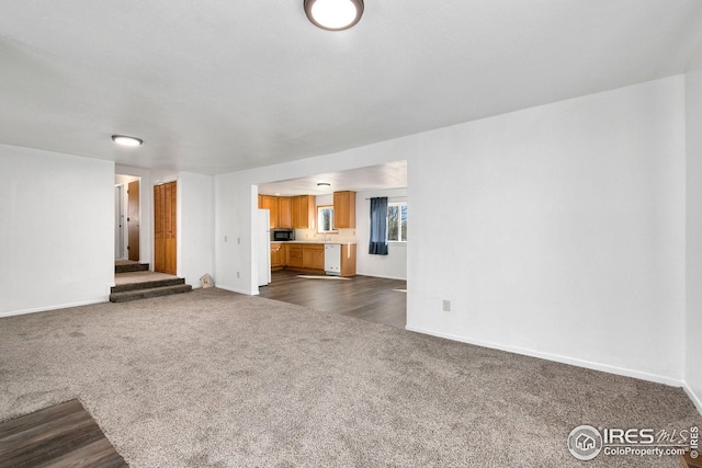 unfurnished living room with dark colored carpet and baseboards